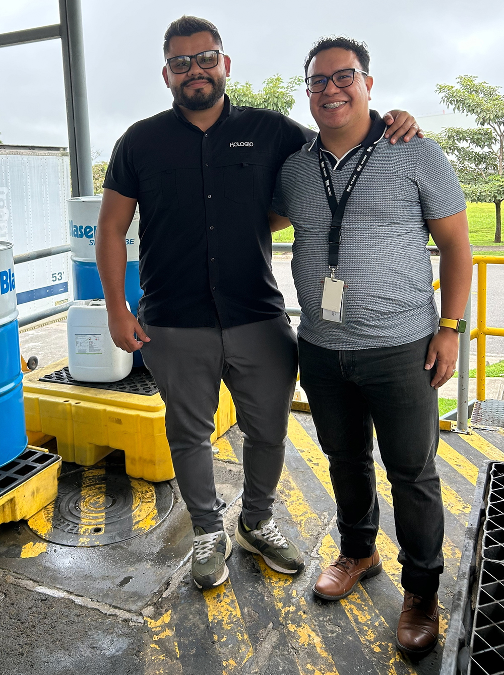 Costa Rica colleagues who implemented an oil recovery project at the site. Two individuals stand next to each other outside in the sun.