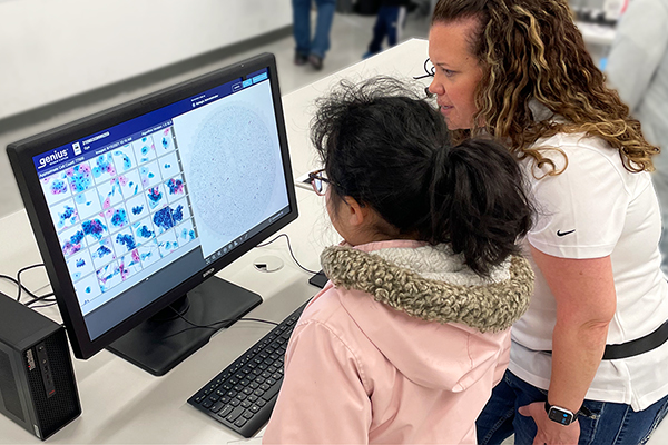 Volunteer shows student the Genius AI Digital Diagnostics platform.