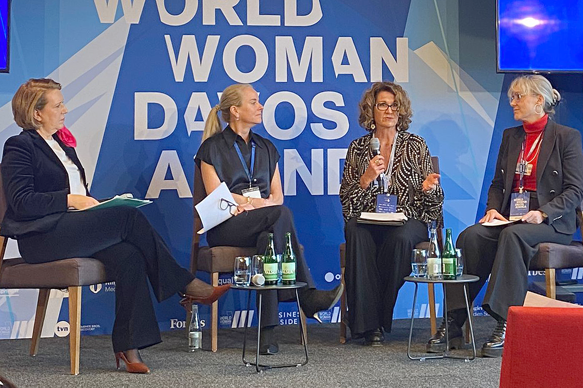 Four women sit on a stage in chairs for a panel discussion.
