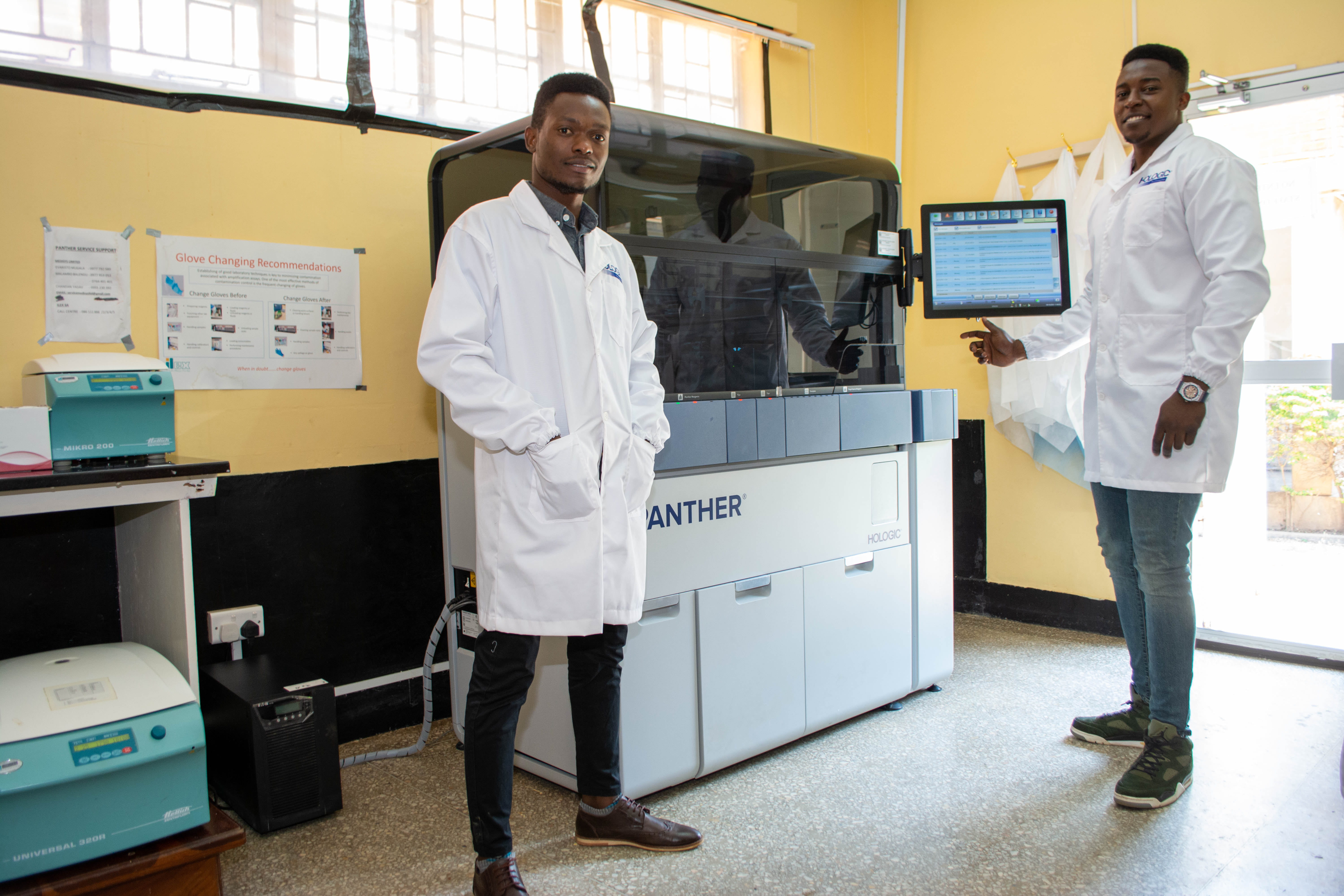 Lab technicians standing with Panther system in a lab setting.