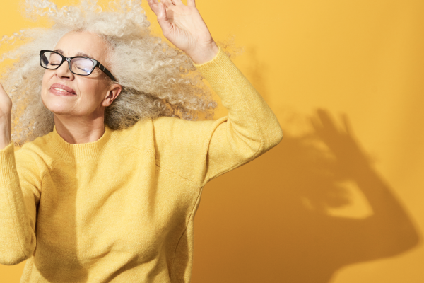 Woman dancing in front of yellow background