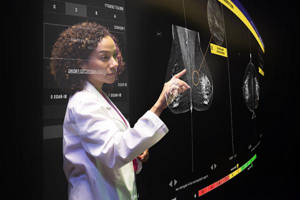 Healthcare technician touching display screen showing x-ray images.