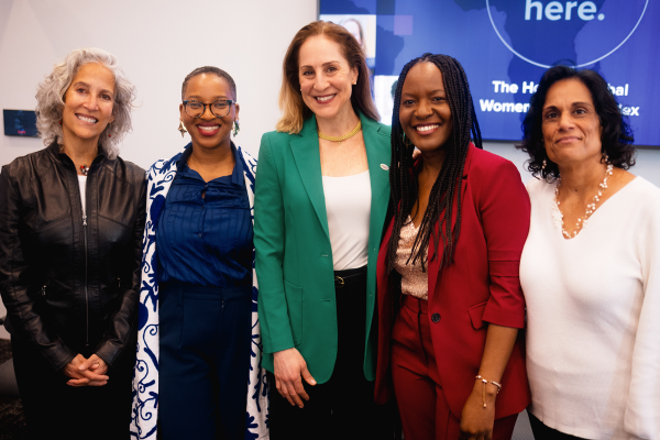 Group of five women standing next to each other smiling. 