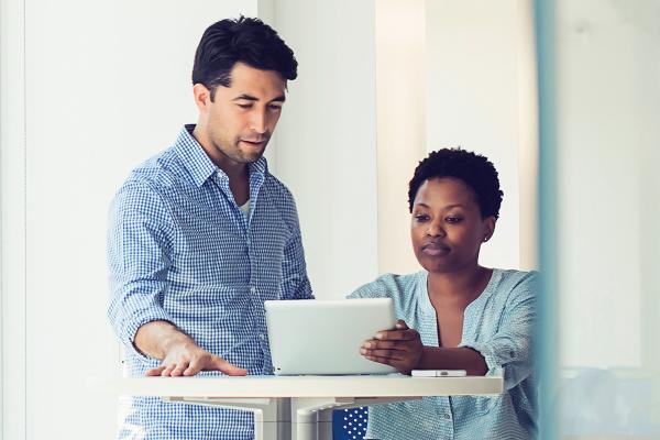 Man and woman looking at a tablet in an office.