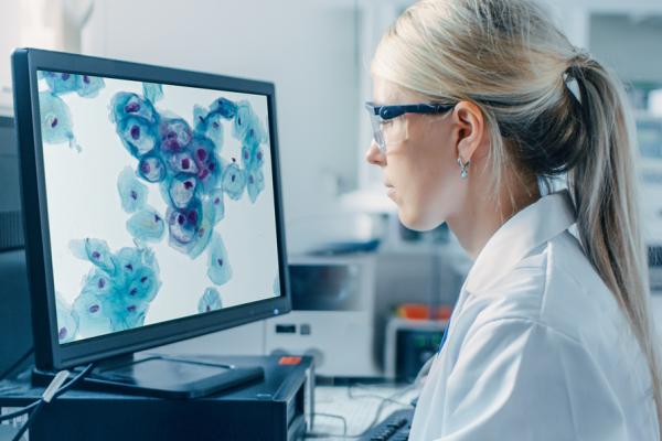 Technician looking at scans on monitor display in lab setting.