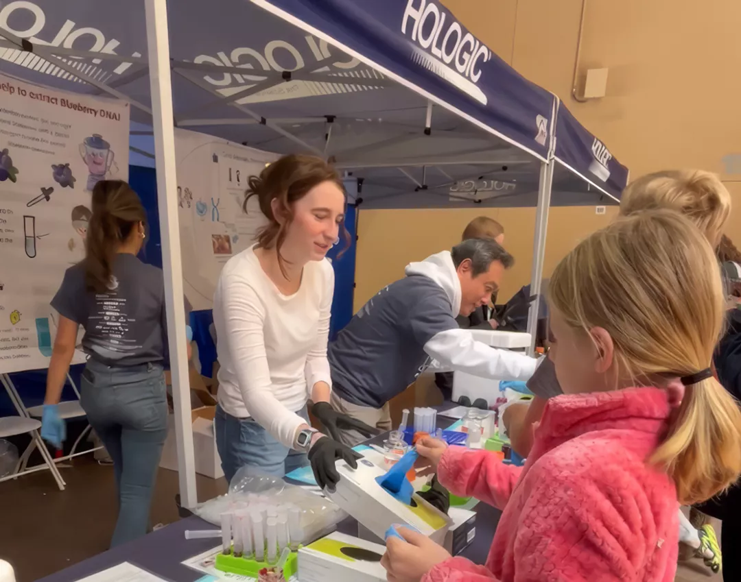 Hologic Volunteer giving gloves for a test demonstration