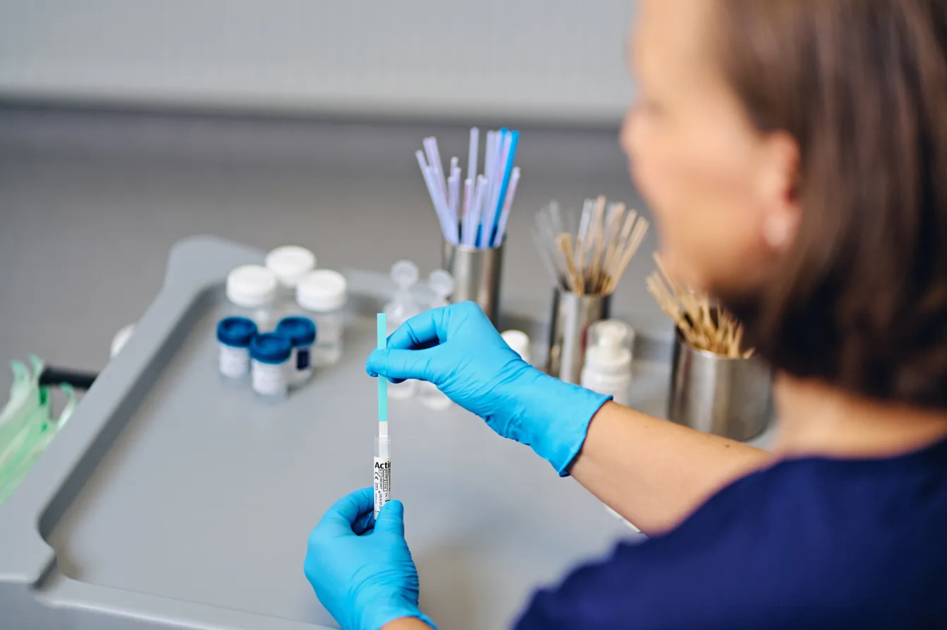 Technician using medical equipment in lab setting.