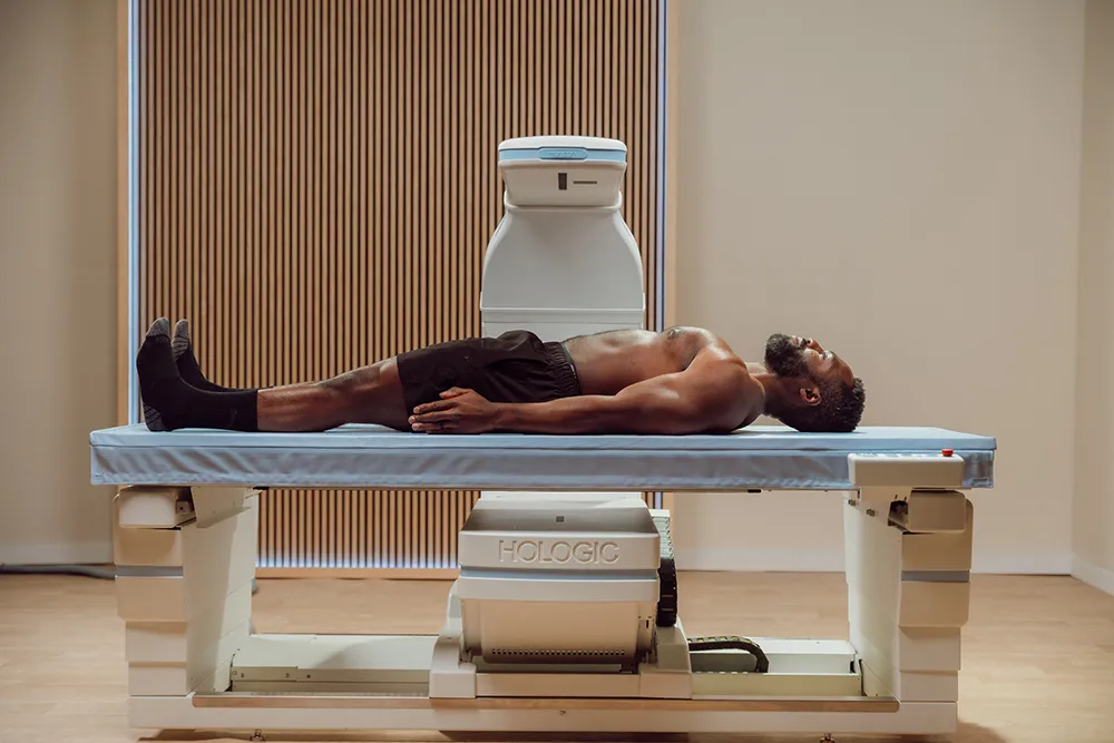 Man laying on exam table with medical device scanning him in exam room setting.