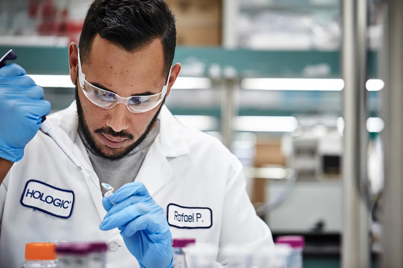 Group of people standing in a shape on grass and waving