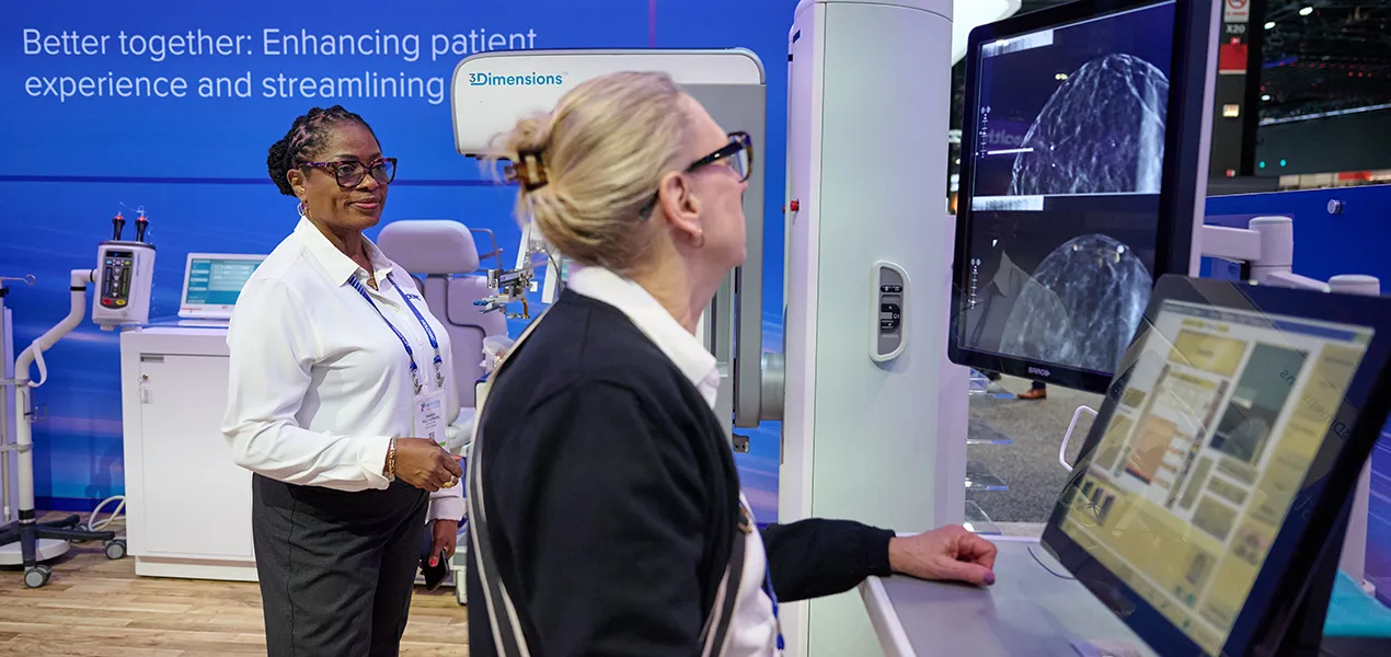 Women standing if front of a monitor displaying mammogram images.