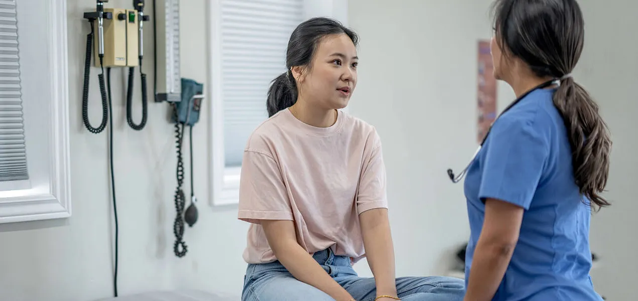 Woman sits on an exam table in a doctor's office.