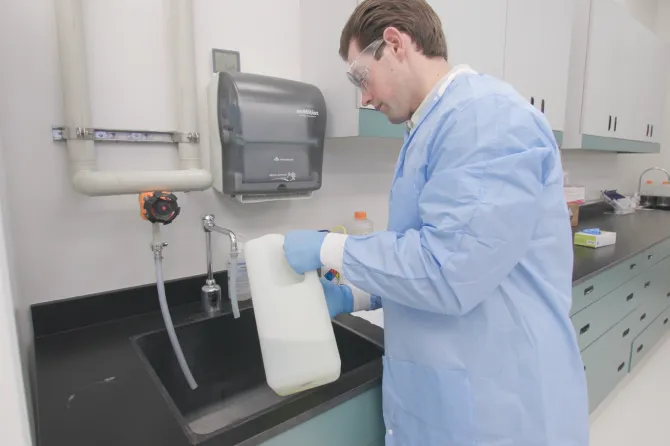 Technician working at sink in lab setting.
