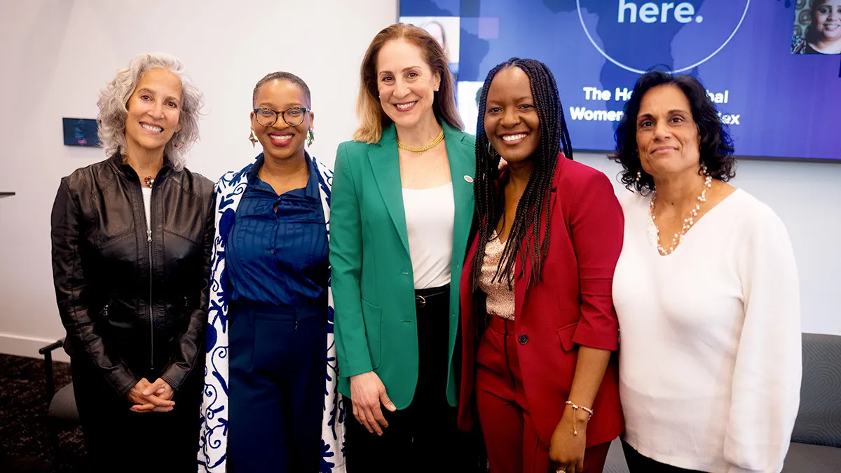 Group of five women standing next to each other smiling. 