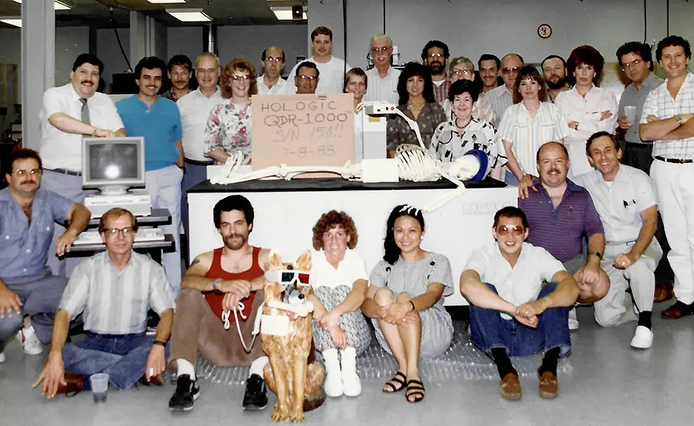 Group of people stand around a medical device.