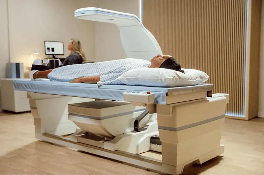 A woman in a hospital gown lays on a medical device. 