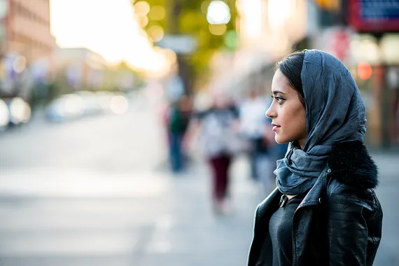 Woman standing outside on a city sidewalk.
