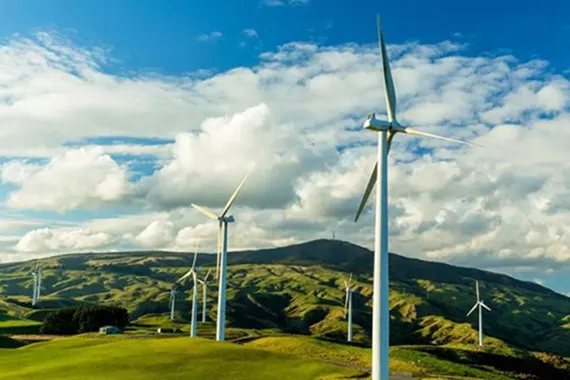 View of windmill farm with large hills and sky in the background