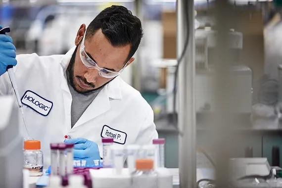 Technician working with vials in lab setting.