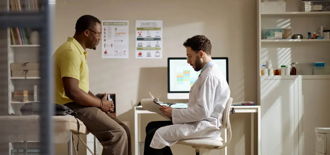 Man in yellow shirt talks with doctor.