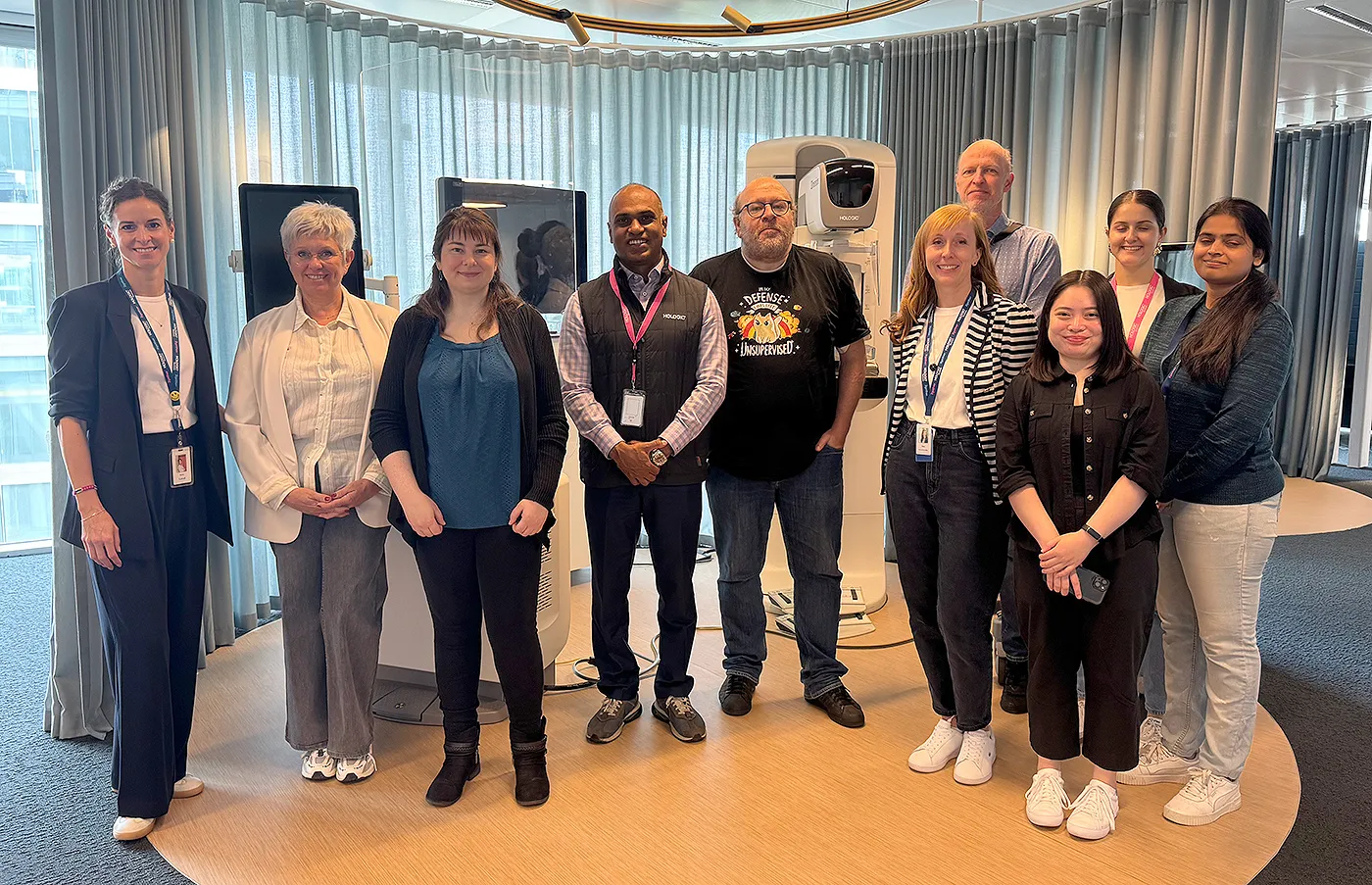 Group of people stand around a mammography machine. 