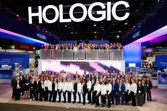 Large group photo on convention floor standing in company themed booth