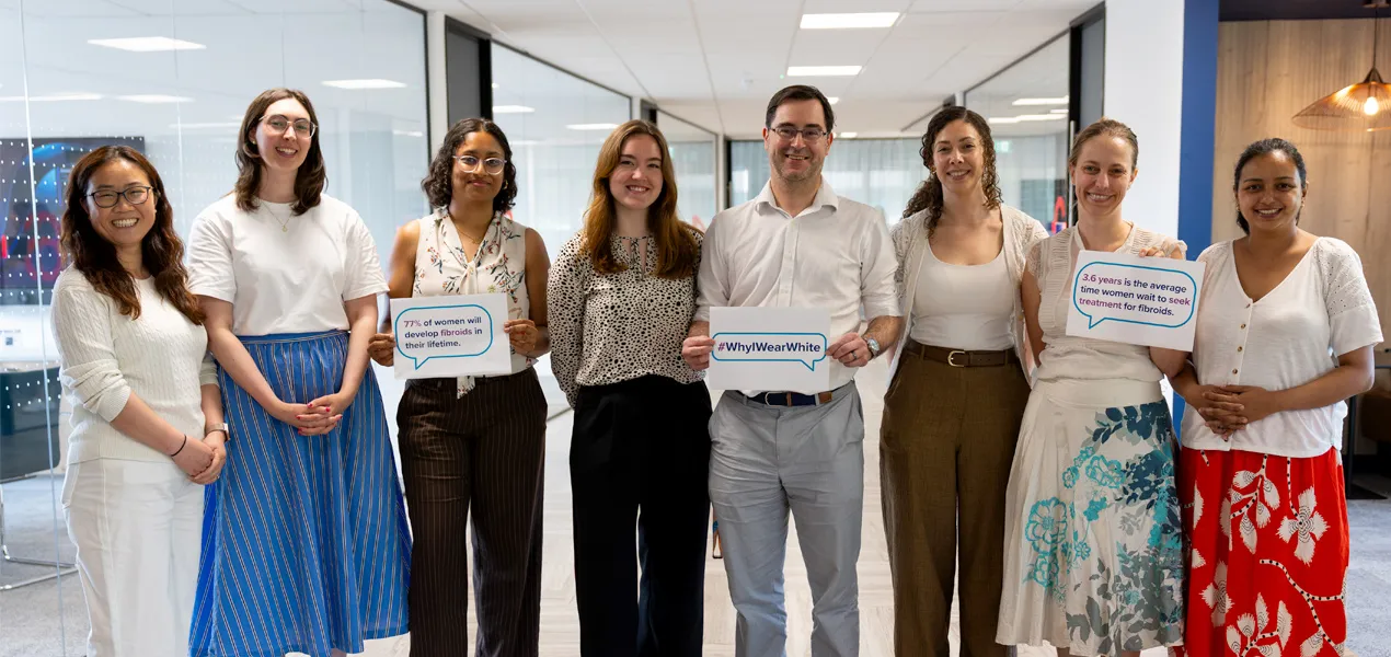 Hologic employees wearing white and holding signs at a company event raising awareness of uterine fibroids.