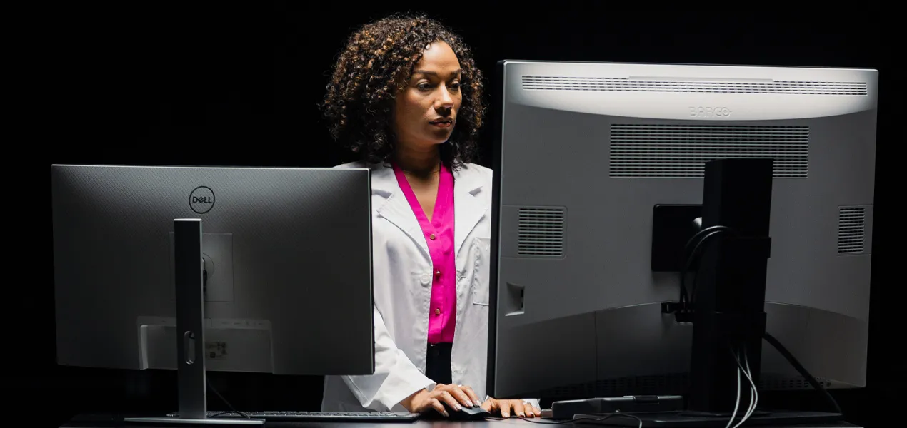Doctor reviews mammogram images on monitors.