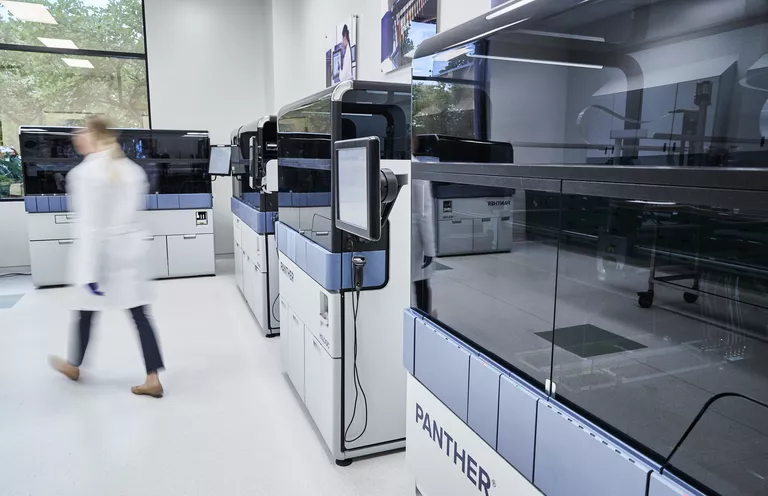 person walking away from a panther in a lab