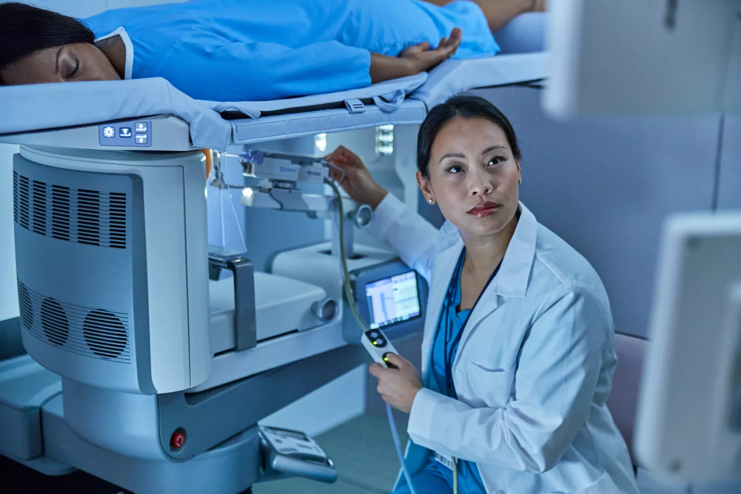 Woman lying down on breast imaging system with technician