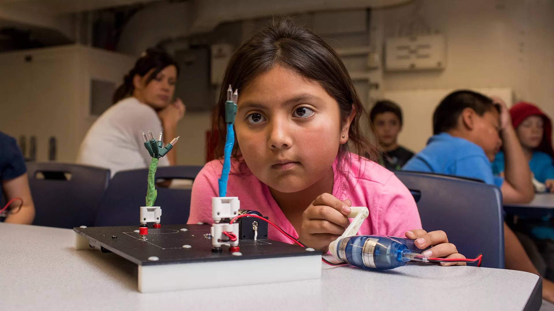 Young students working on a project with teacher in a classroom.