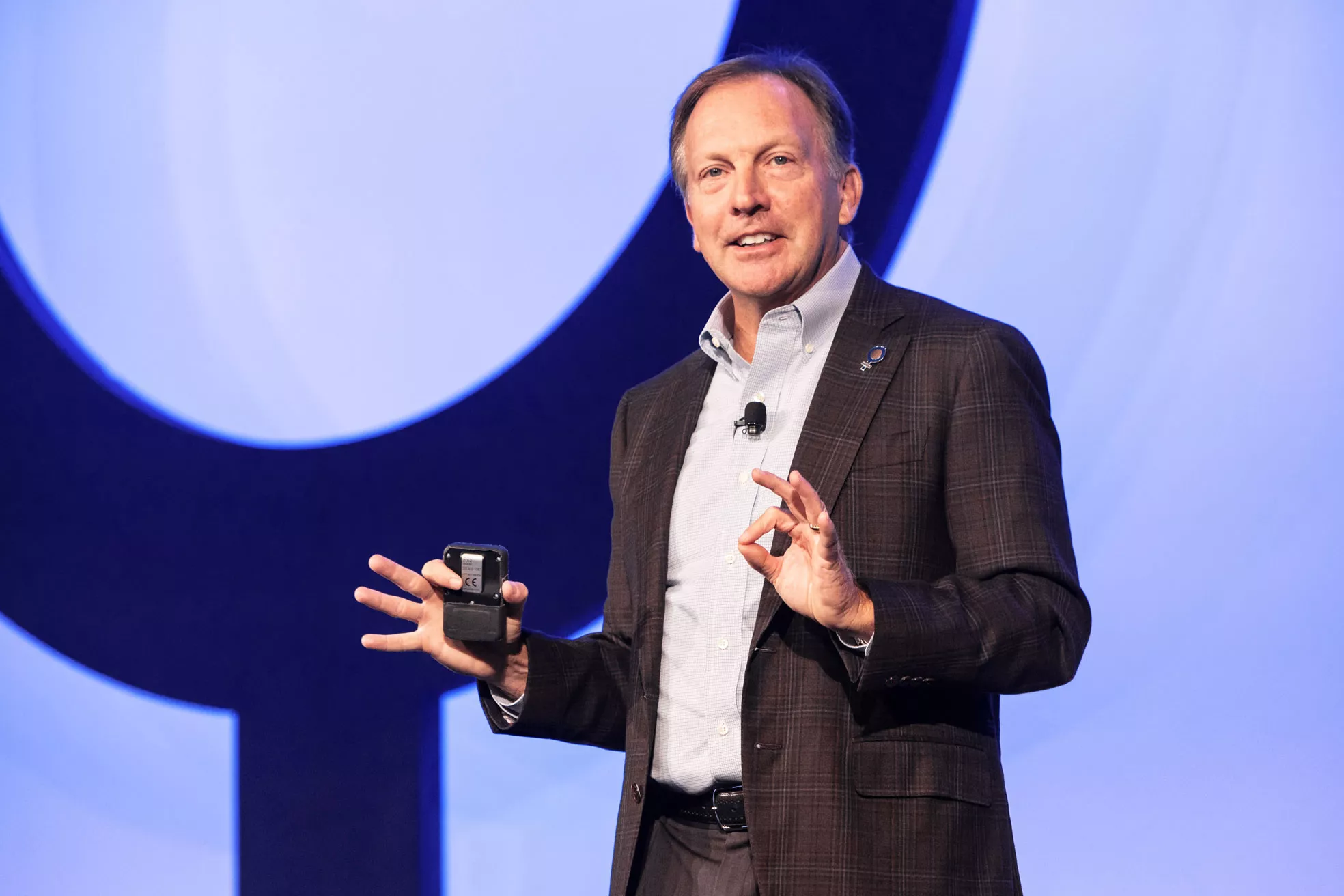 Photo of CEO speaking on a stage holding a presentation remote.