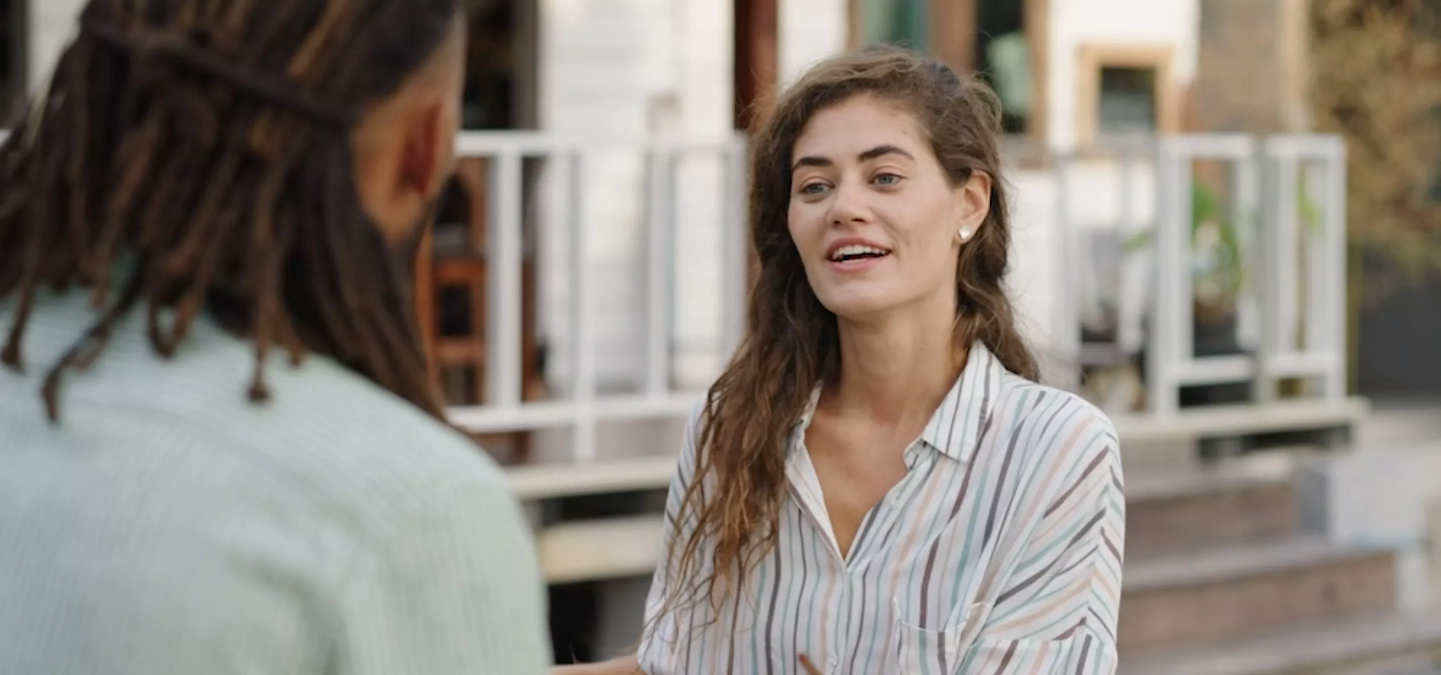 Woman speaking to a man outside near a house during the day.