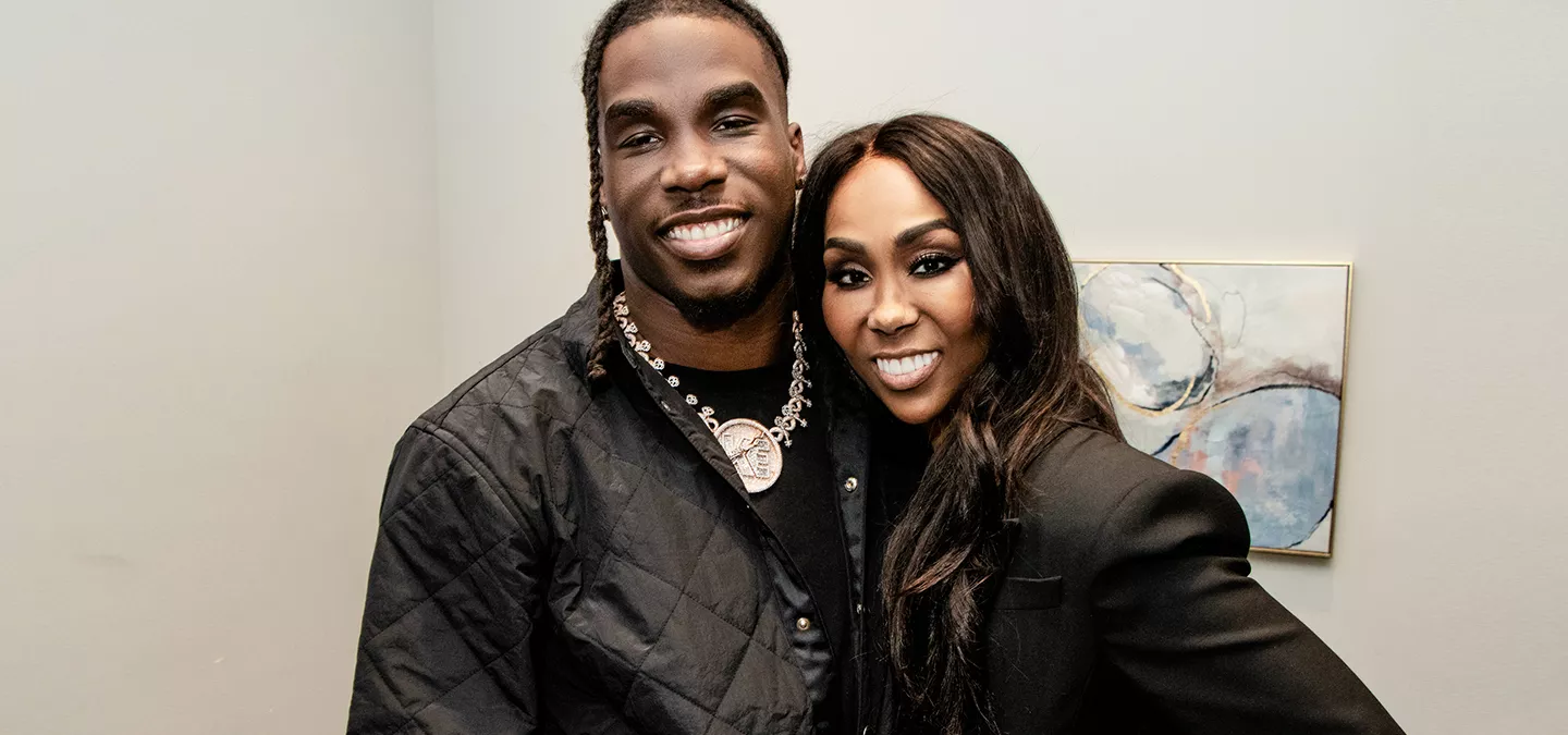 Man and woman smiling at camera standing on a football field