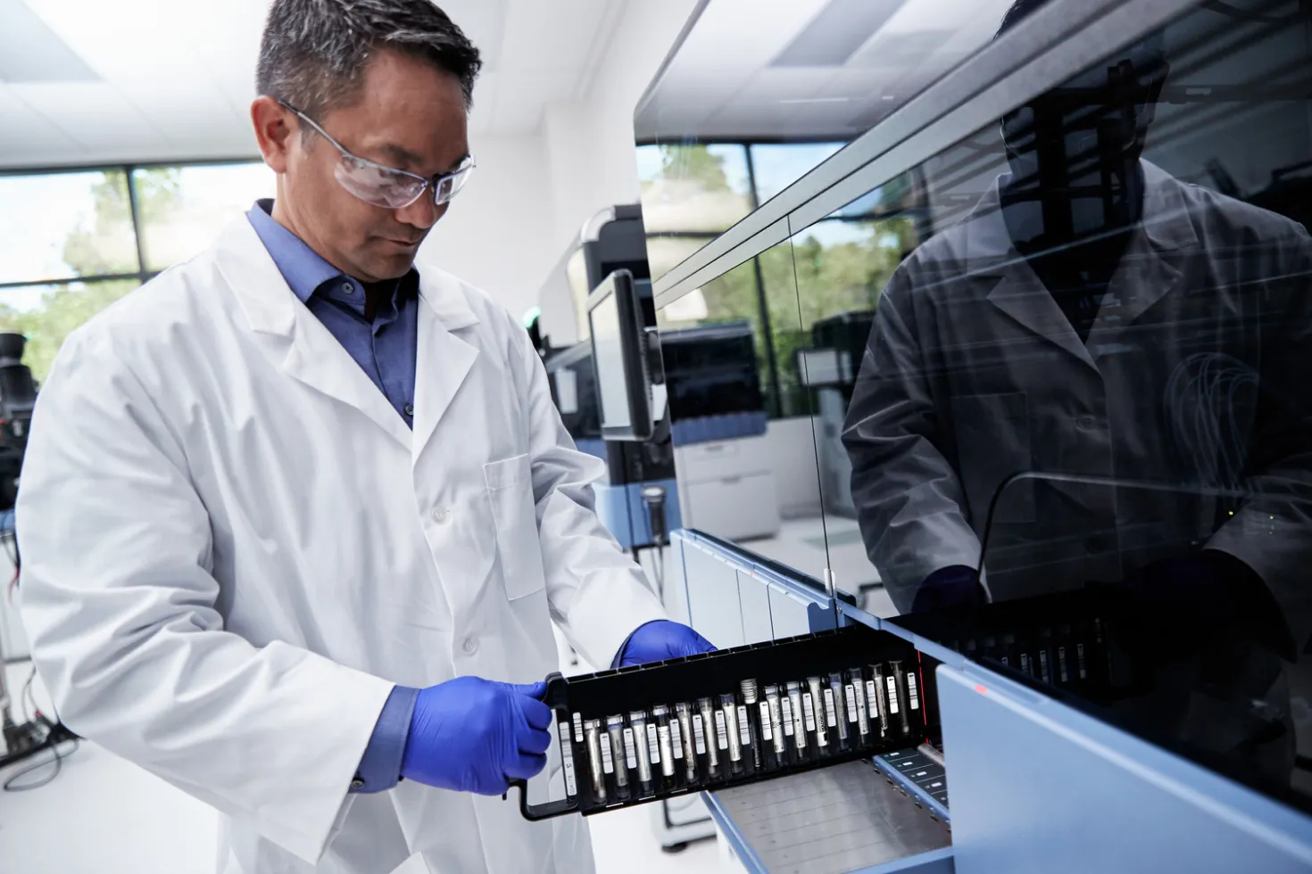 Lab technician loading a vial tray into a medical device in a lab setting.
