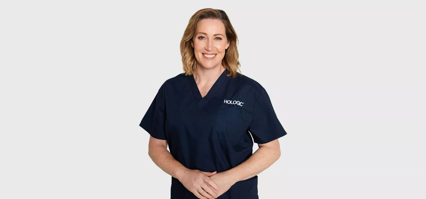 Female health provider stands and smiles in front of a blank background