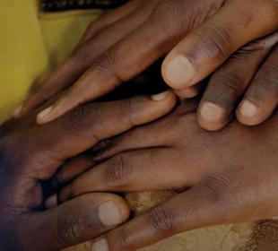 Close up picture of different hands holding each other.
